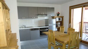 Een moderne keuken met grijze kastjes, een houten eettafel en stoelen.