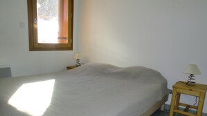 Een slaapkamer met een bed, nachtkastje, lamp en raam.