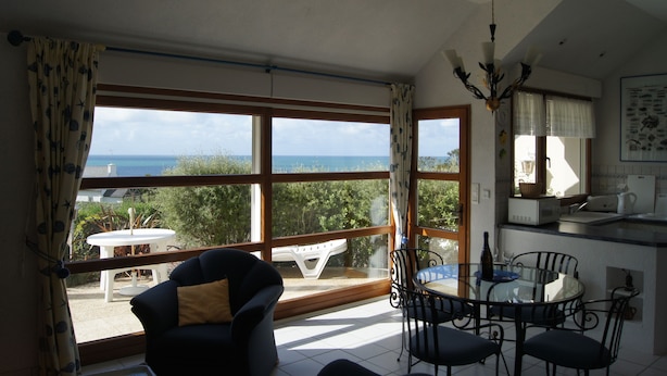 Un comedor con vista al mar, una cocina con microondas y una mesa de comedor con sillas.