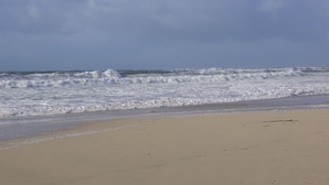 Una playa con olas rompiendo en la orilla bajo un cielo nublado.