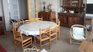 Un comedor con una mesa redonda, sillas de madera, un armario y un televisor.