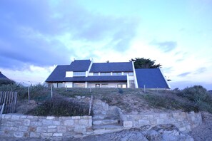 A modern house with a stone retaining wall and a staircase leading up to the entrance.