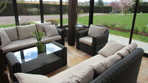 A covered patio area with wicker furniture, including a sofa and armchairs, and a small table.