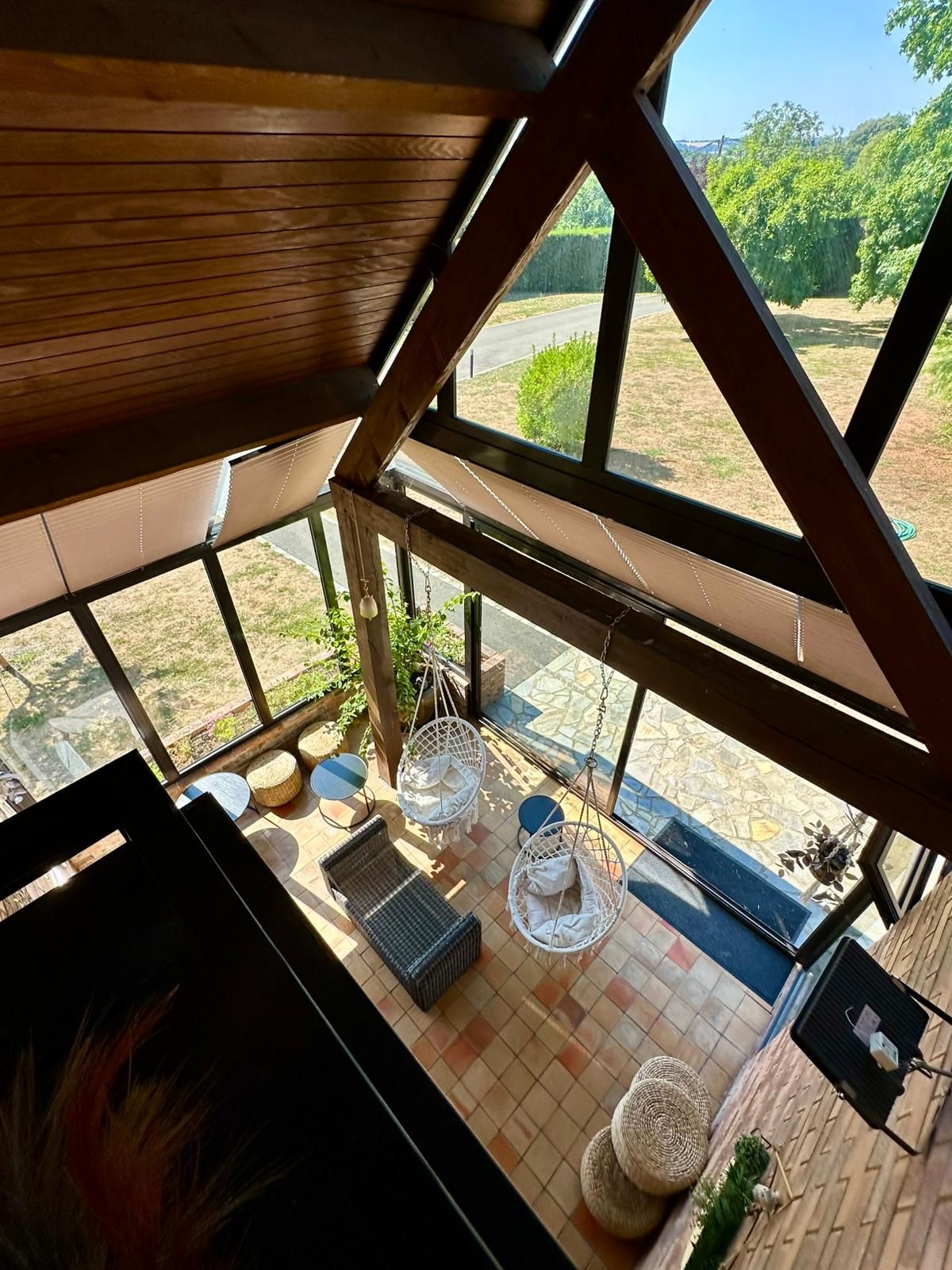 Una habitación con un ventanal grande, muebles de mimbre y piso de baldosas.