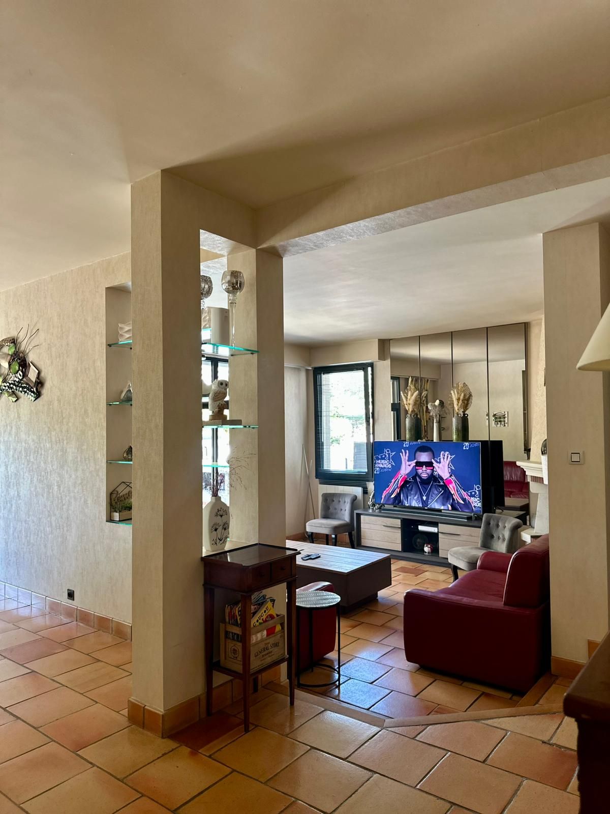 Una sala de estar con televisor, un sofá rojo, una mesa de centro y una estantería.