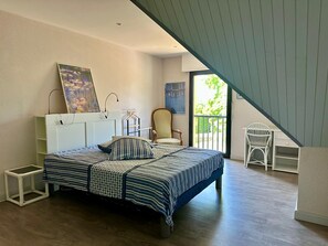 Un dormitorio con cama, una silla, un escritorio y un balcón.