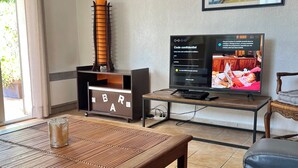 Un salon avec une table basse en bois, un canapé, un téléviseur et un tableau encadré accroché au mur.