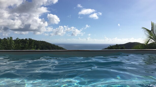 Une piscine aux eaux cristallines, offrant une vue sur l’océan et les collines.