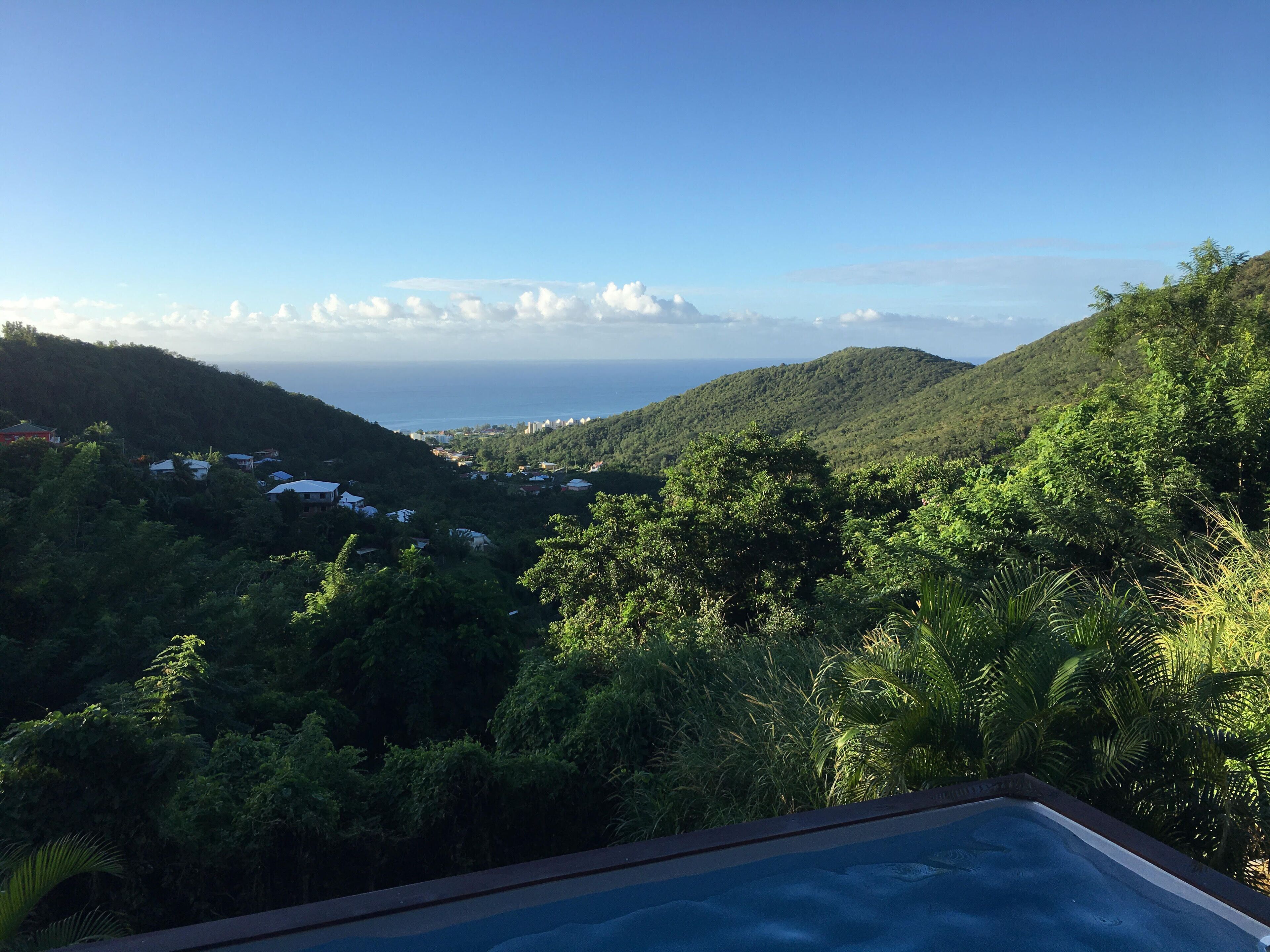 A pool with a view of a lush green landscape and distant hills.