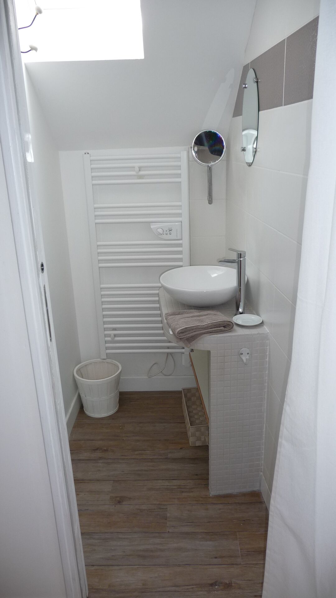 A compact bathroom with a white sink, a mirror, and a toilet.