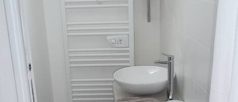 A compact bathroom with a white sink, a mirror, and a toilet.