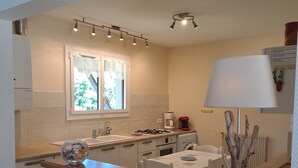 Een moderne keuken met een centraal eiland, een raam met gordijnen en een ingebouwde kookplaat.