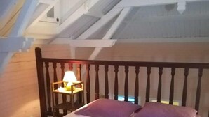A bedroom with a wooden bed frame, white walls, and a sloped ceiling.