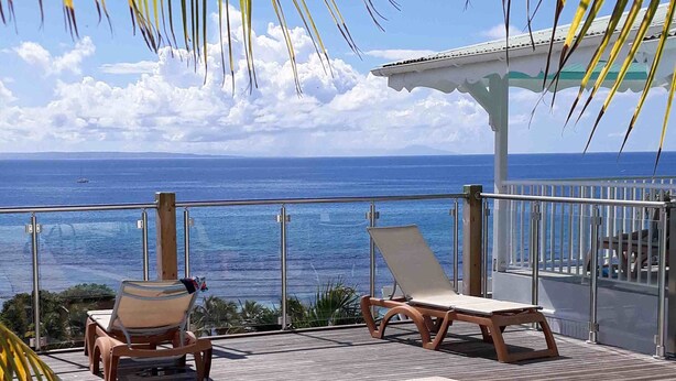 A pool area with lounge chairs and a view of the ocean.