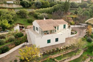 Une maison blanche à deux étages, avec un toit en tuiles, un balcon et un jardin.