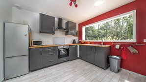 Una cocina moderna con armarios grises, microondas, horno y ventana con vistas a árboles.
