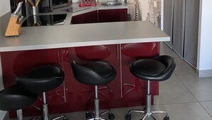 Una cocina moderna con una isla central, taburetes de bar, microondas y un lavabo.