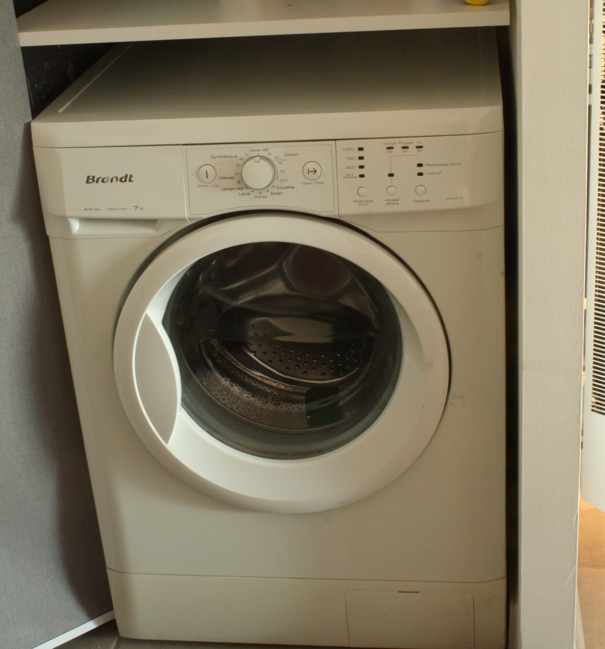 A white Brandt front-loading washing machine with a control panel featuring various settings and buttons.