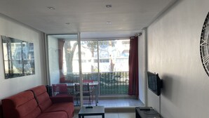 Una sala de estar moderna con un sofá rojo, una mesita y un televisor montado en la pared.