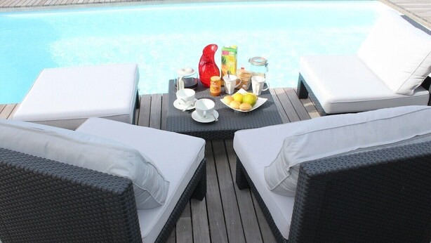 A poolside area with two white cushioned lounge chairs, a table with breakfast items, and a clear view of the pool. - Villa Bel Plaisi - Tropical villa with private pool - 7 pers - Le Moule (Le Moule)