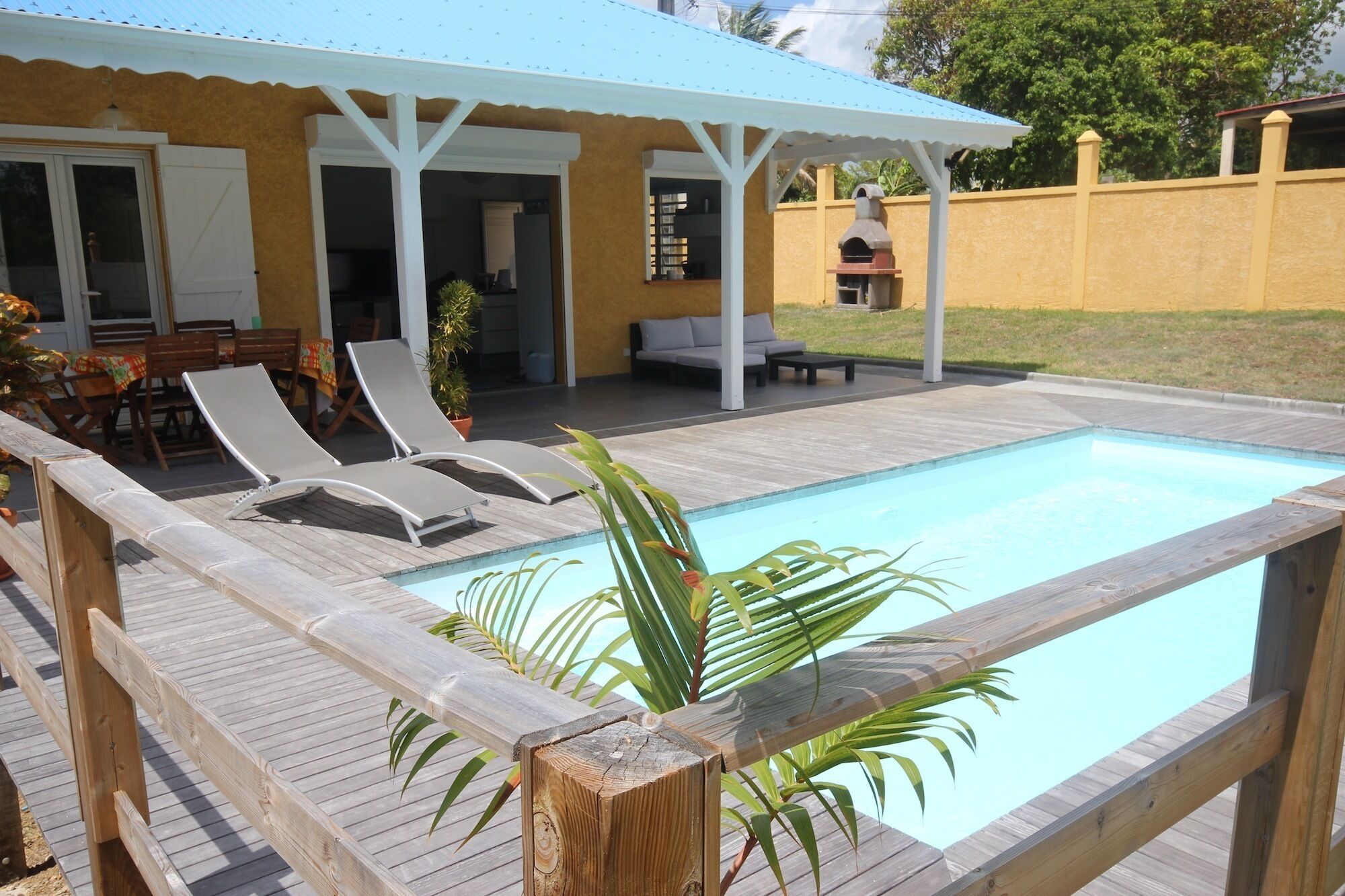 A pool area with a wooden deck, lounge chairs, and a covered seating area.