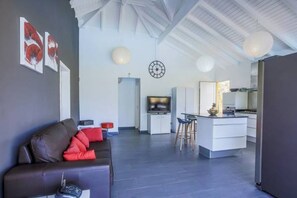 A modern living room with a sofa, a television, and a kitchen area in the background. - Villa Bel Plaisi - Tropical villa with private pool - 7 pers - Le Moule (Le Moule)