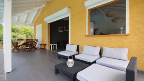 An outdoor patio area with a yellow wall, white furniture, and a dining set. - Villa Bel Plaisi - Tropical villa with private pool - 7 pers - Le Moule (Le Moule)