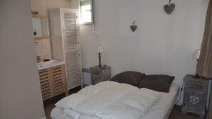 Un dormitorio con cama, mesitas de noche, armario, espejo y una pared decorada con corazones.