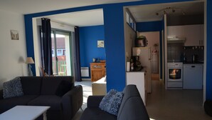 Una sala de estar con sofá, una mesa de centro y vista a la cocina.