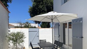 Eine Terrasse mit Tisch, Stühlen und einem Sonnenschirm, sowie eine Tür.