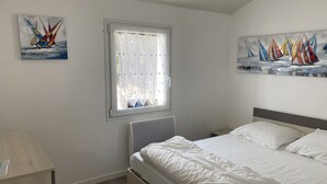 Ein Schlafzimmer mit einem Bett, einem Fenster mit Vorhängen und zwei Bildern an den Wänden.