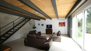 A spacious living area with a staircase, a large window, and a flat-screen TV.