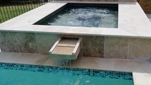 A spa area with a hot tub and a small waterfall feature.