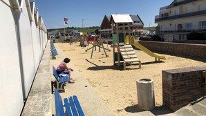 A beachside playground with a slide and climbing structures, a sandy area, and a row of blue benches along the edge. - Villa vent d'Amont, house on enclosed land, sea view, sleeps 4, pets allowed (Quiberville)