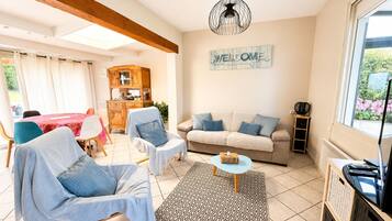 A living room with a sofa, chairs, a coffee table, a cabinet, and a 'WELCOME' sign.