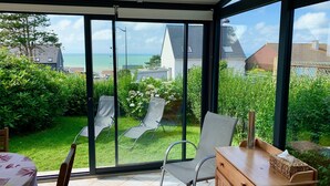 A sunlit room with a view of the sea, a wooden cabinet, and two lounge chairs. - Villa vent d'Amont, house on enclosed land, sea view, sleeps 4, pets allowed (Quiberville)