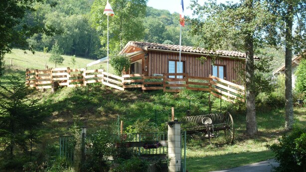 A wooden cabin with a sloped roof, a wooden deck, and a small garden area. - The cottage Baragnou lantern Nalzen (Nalzen)