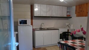A compact kitchen with white cabinets, a microwave, a sink, and a table with a floral tablecloth. - Have a breath in our mountains. (La Bresse)