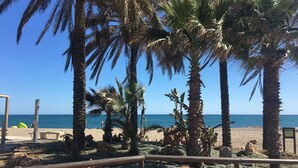 A beach with palm trees, a sandy area, and a wooden fence. - Superb villa Sea views Heatable pool 5 min walk to beach & all amenities (La Cala de Mijas)