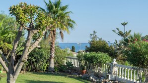 A garden with palm trees, a white fence, and a view of the sea. - Superb villa Sea views Heatable pool 5 min walk to beach & all amenities (La Cala de Mijas)