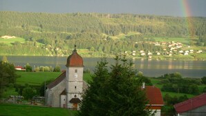 Eine Kirche mit einem Glockenturm, umgeben von üppigem Grün und einem See.