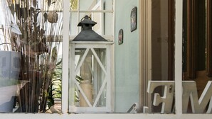 Un edificio con un porche cubierto, un farol y una puerta con marco de madera.