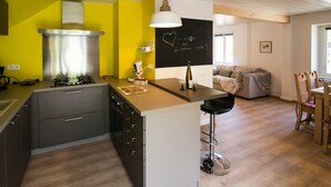 Una cocina moderna con estufa a gas, extractor de acero inoxidable y una zona de bar con un taburete.