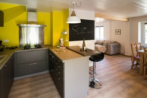 Eine moderne Küche mit einem Gasherd, einer Edelstahl-Dunstabzugshaube und einer Bar mit einem Hocker.