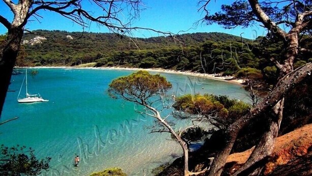 A coastal landscape with clear turquoise waters, a boat, and a beach. - Hyères on the Peninsula Giens, Beach and swimming pool facing Porquerolles *** ! (Hyères)