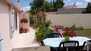 A patio with a table and chairs, surrounded by potted plants and flowers. - house by the sea on the Vendée coast quiet good plan (Bouin)