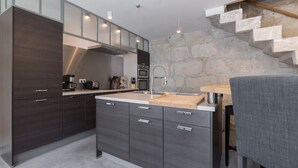 A modern kitchen with dark cabinetry, a stainless steel sink, and a stone wall staircase. - Quiet home in the heart of the Alpilles with private pool (Eyragues)