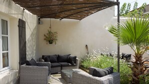 A covered outdoor seating area with wicker furniture and a hanging plant. - Quiet home in the heart of the Alpilles with private pool (Eyragues)