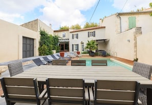 Un espace extérieur aménagé avec une piscine, du mobilier de jardin et un bâtiment doté d’un toit en tuiles.