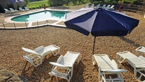A pool area with white lounge chairs and a large umbrella. - Hameau-Montplaisir, Béziers (Béziers)